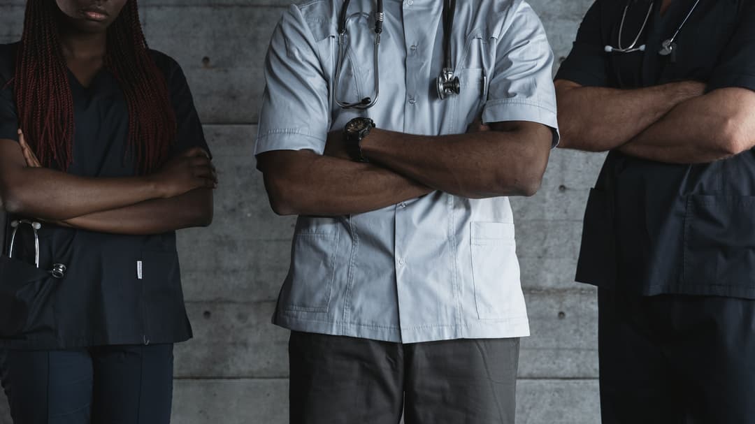 Three medical providers in scrubs standing together as a team